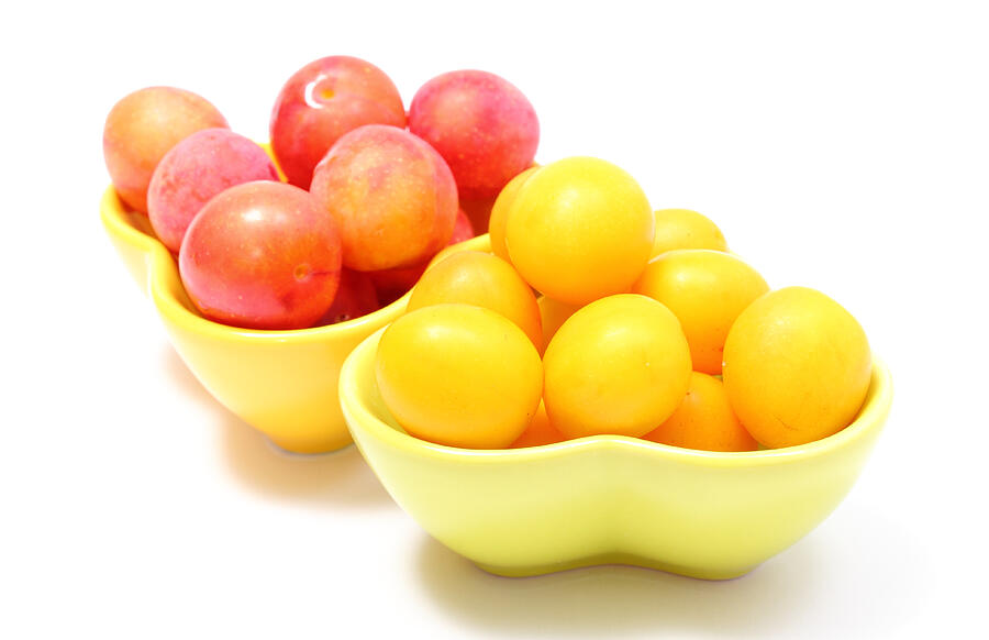 Heap of red and yellow mirabelle in bowls. White background Photograph by Ratmaner