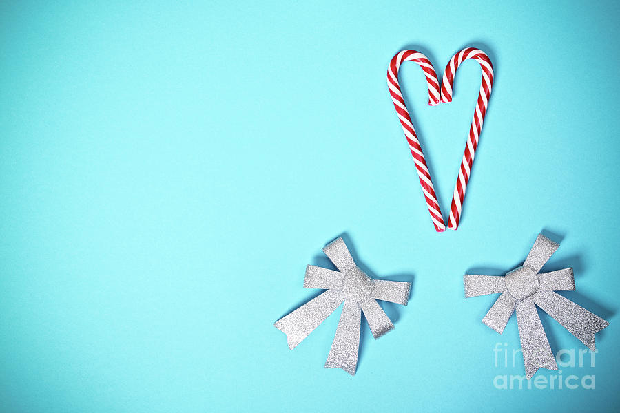 Heart shaped candy canes and bows on pastel blue background Photograph by Mendelex Photography