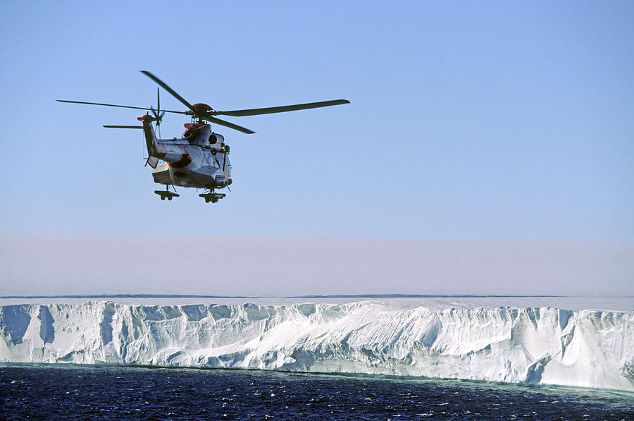 Helicopter over iceberg and sea Photograph by Johner Images