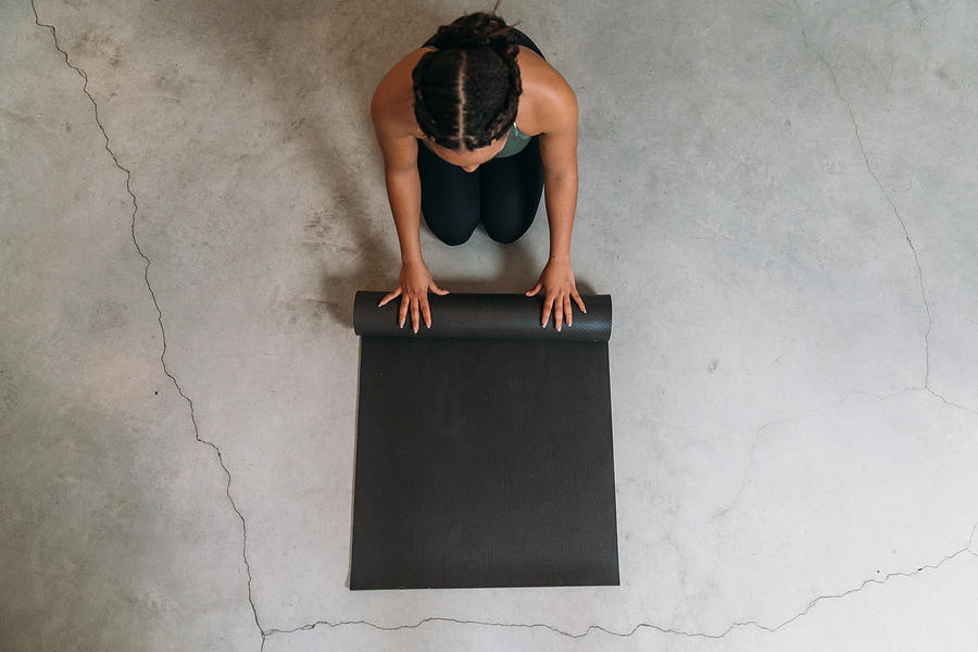 High angle view of a young adult woman closing a yoga mat Photograph by FilippoBacci