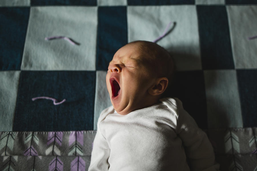 High angle view of cute baby girl yawning while sleeping on bed Photograph by Cavan Images