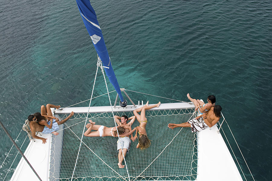 High angle view of friends sunbathing on sailboat Photograph by Alberto Guglielmi