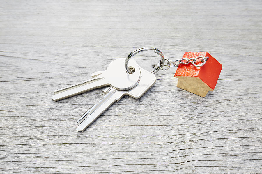 High angle view of keyring with a small red house and keys on wooden background Photograph by The_burtons
