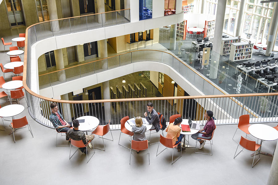 High angle view of modern college interior, students sitting around tables Photograph by JohnnyGreig