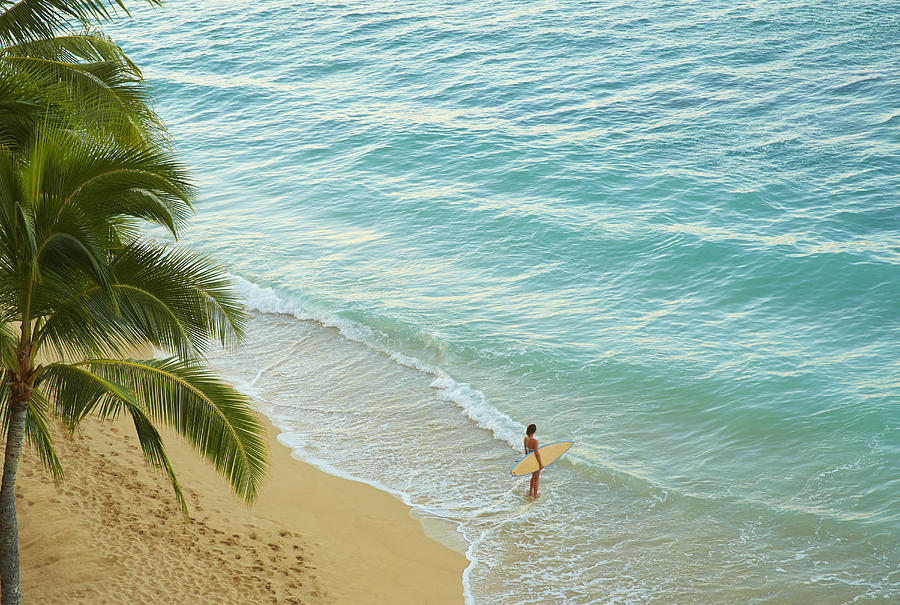 High angle view of Pacific Islander woman carrying surfboard on beach Photograph by Colin Anderson Productions pty ltd