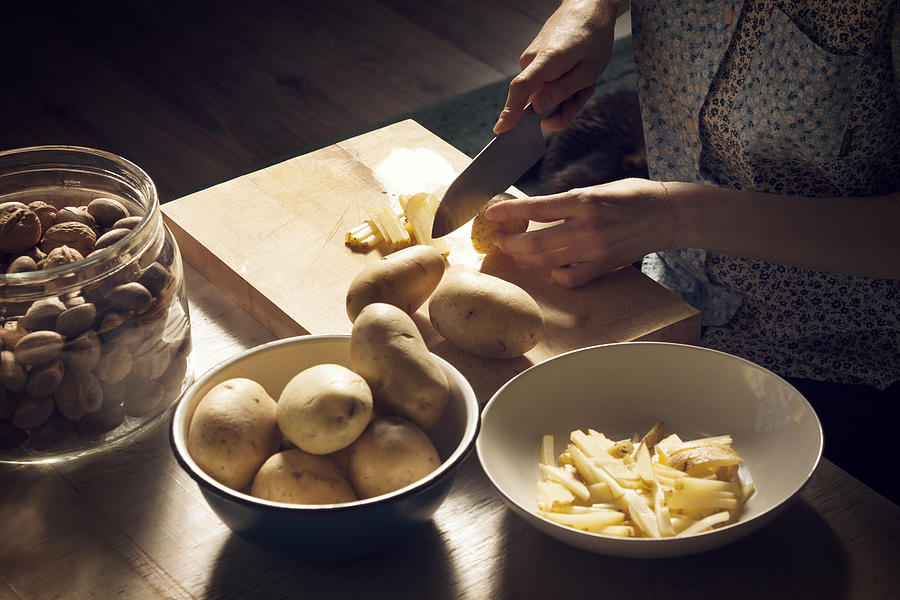 High angle view of woman cutting potatoes on cutting board at home Photograph by Cavan Images