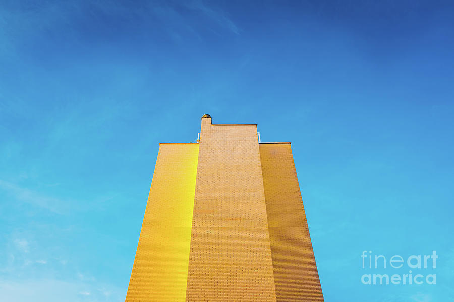 High brick building, warm and yellow at sunset, with the backgro Photograph by Joaquin Corbalan