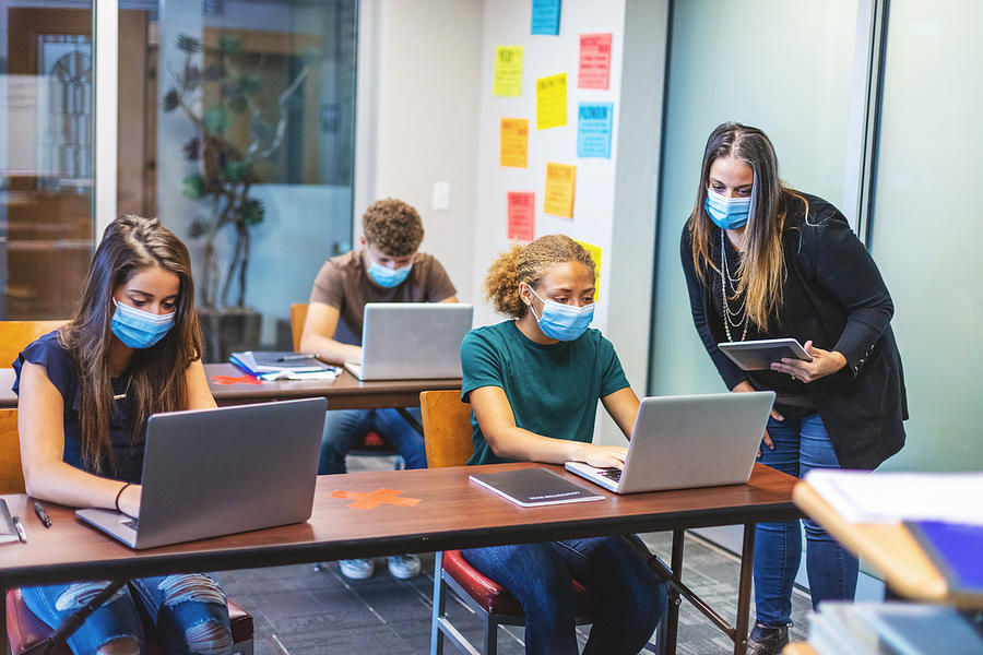 High School Students and Teacher wearing face masks and social distancing in Classroom Setting working on laptop technology Photograph by Eyecrave
