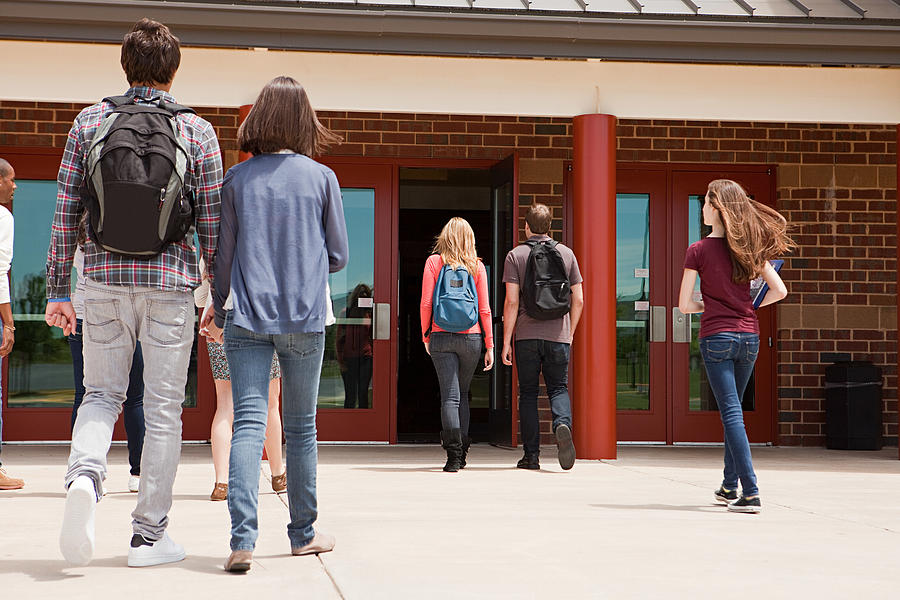 High school students entering school building Photograph by Image Source