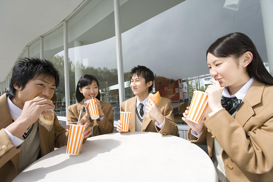 High school students having lunch at terrace, smiling Photograph by Daj