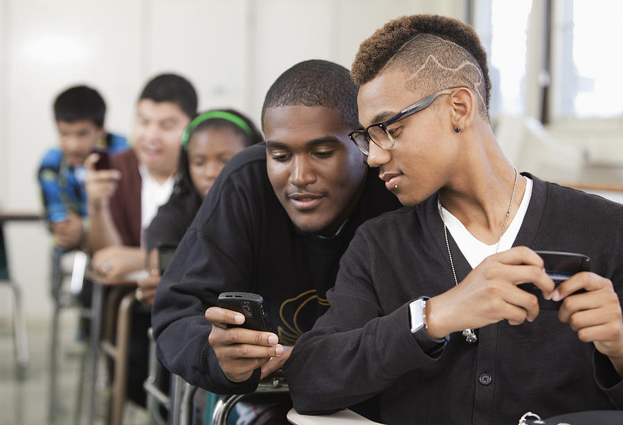 High school students using cell phones in classroom Photograph by Hill Street Studios