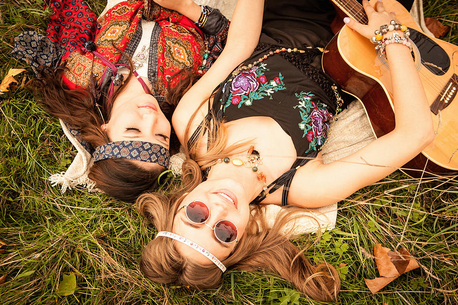 Hippy girls lying in field with guitar Photograph by Jeremy Rice
