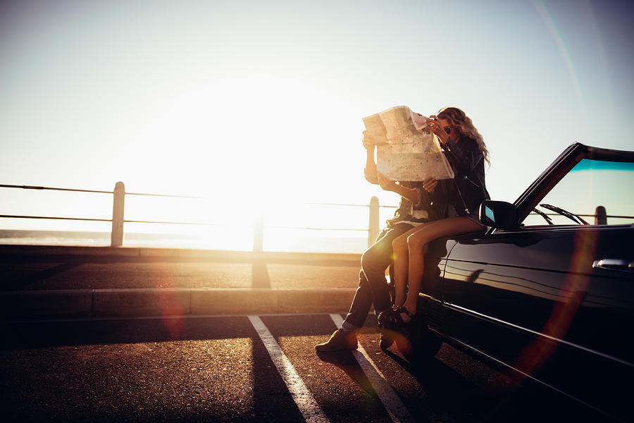 Hipster couple planning their summer seaside road trip with convertible Photograph by Wundervisuals