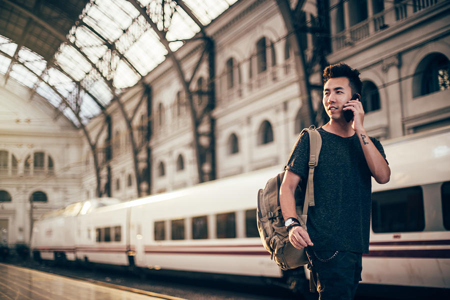 Hipster Man at train station using phone Photograph by South_agency