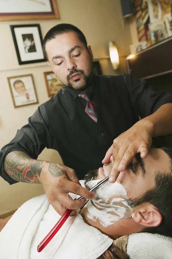 Hispanic barber shaving mans face Photograph by Jinxy Productions
