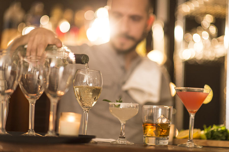 Hispanic bartender pouring drinks at bar Photograph by JGI/Tom Grill
