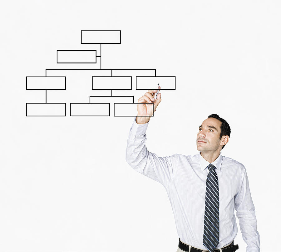 Hispanic businessman drawing flowchart on clear board Photograph by PBNJ Productions