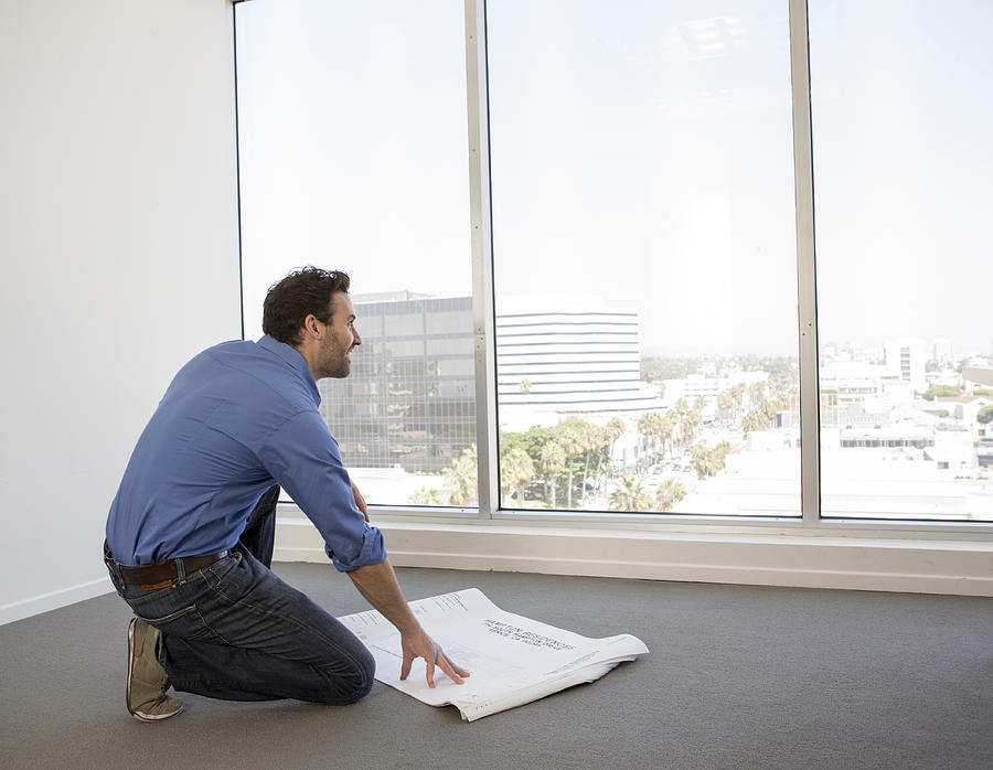 Hispanic businessman examining blueprints in office Photograph by Sam Diephuis