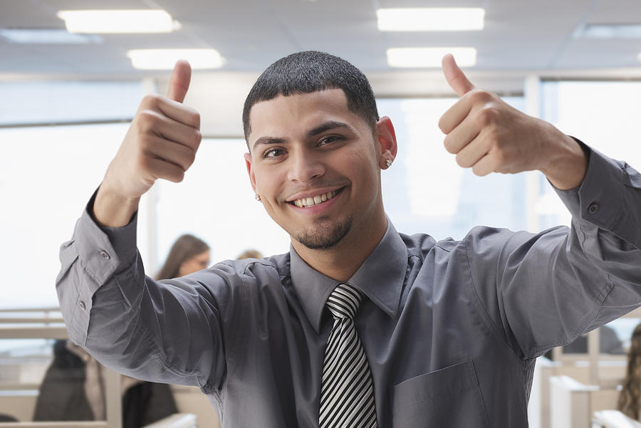 Hispanic businessman gesturing thumbs up in office Photograph by Jose Luis Pelaez Inc