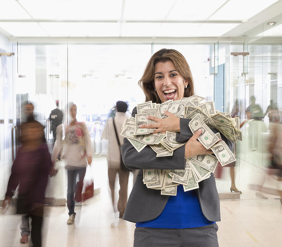 Hispanic businesswoman holding armful of dollar bills Photograph by John M Lund Photography Inc