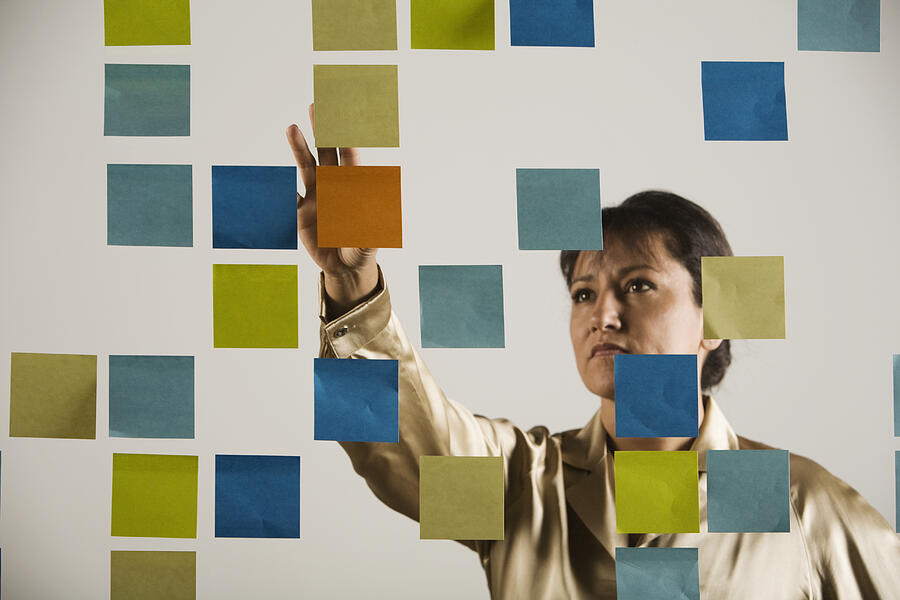 Hispanic businesswoman looking at wall of sticky notes Photograph by Hill Street Studios