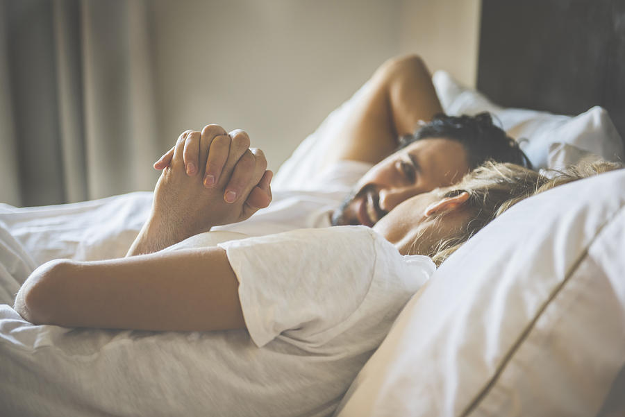 Hispanic couple holding hands in bed Photograph by Jacobs Stock Photography Ltd