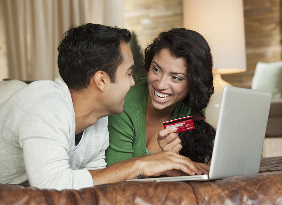 Hispanic couple using credit card online Photograph by Ariel Skelley