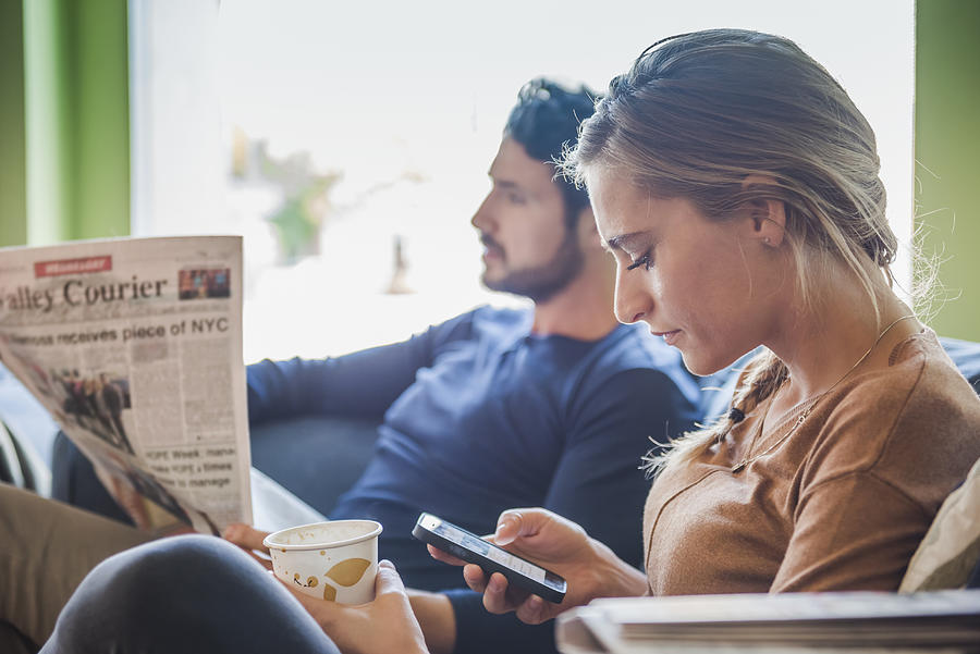 Hispanic couple with newspaper and cell phone in coffee shop Photograph by Jacobs Stock Photography Ltd