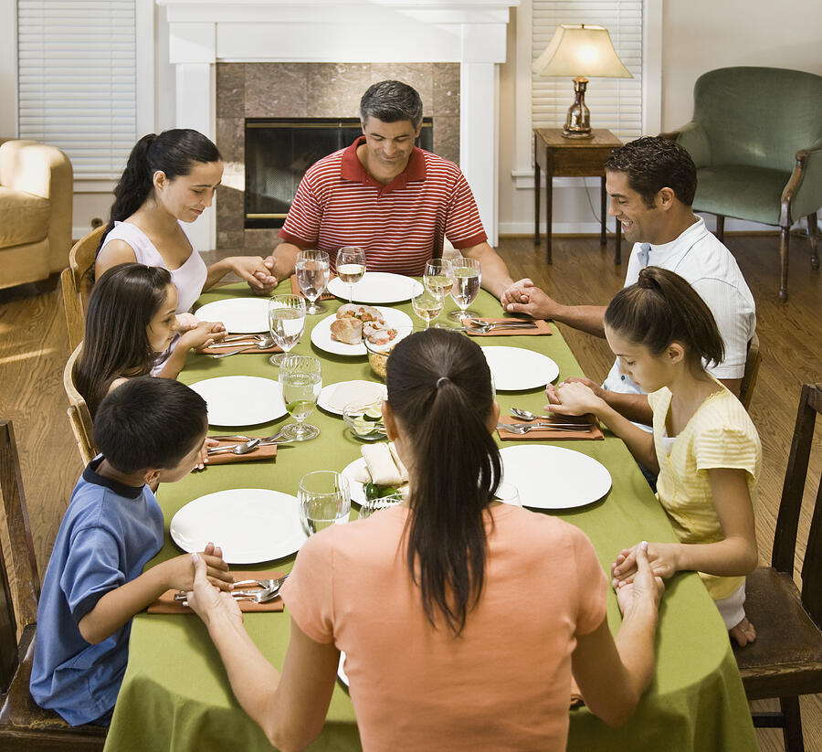 Hispanic family praying at dinner table Photograph by Andersen Ross Photography Inc
