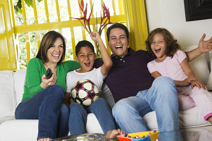 Hispanic family watching soccer on television Photograph by Jon Feingersh Photography Inc
