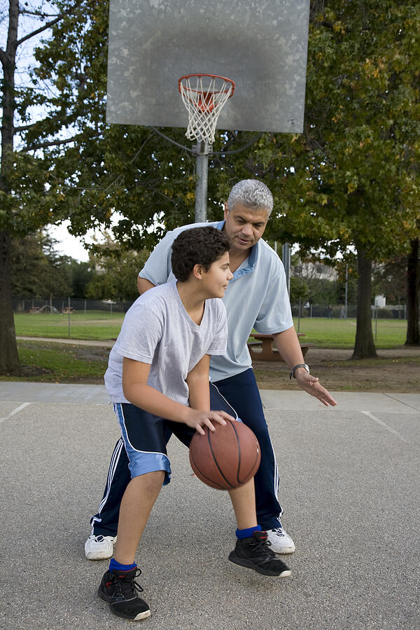 Hispanic father and son playing basketball Photograph by Jacqueline Veissid