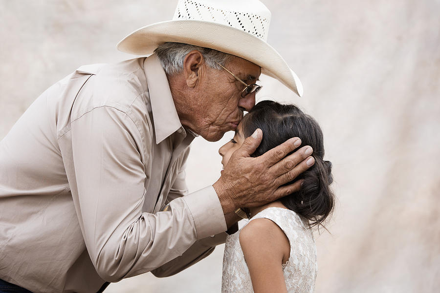 Hispanic grandfather kissing forehead of granddaughter Photograph by Hill Street Studios