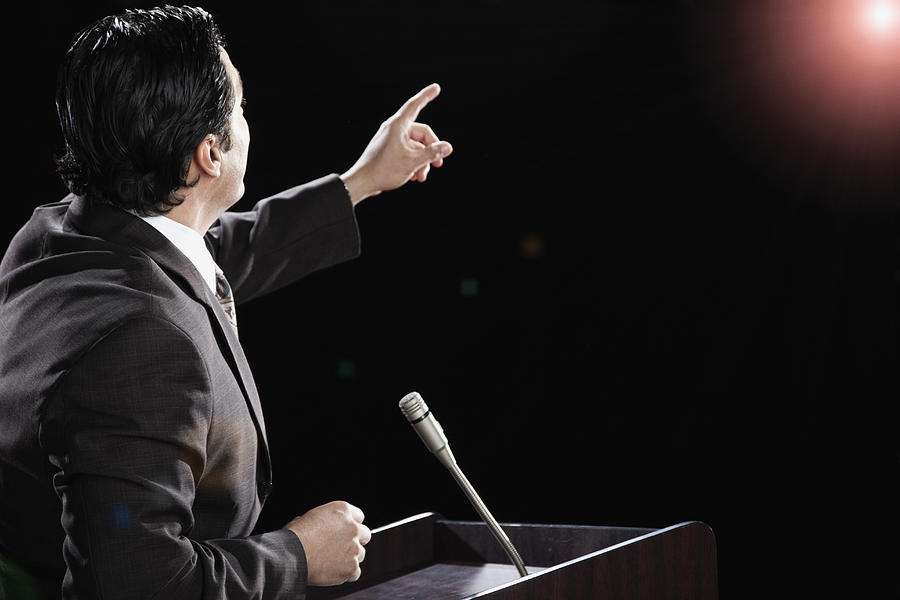 Hispanic man at podium with arm raised Photograph by Hill Street Studios