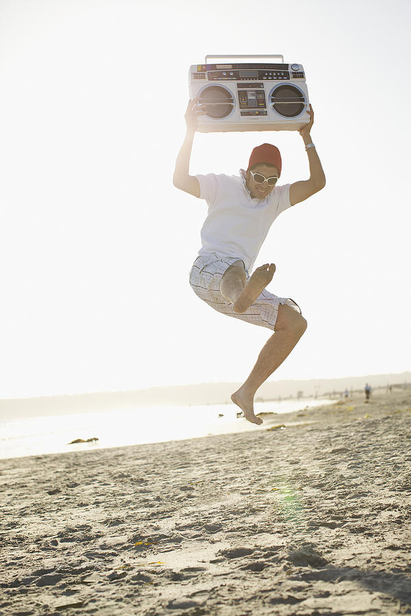 Hispanic man holding boom box and jumping Photograph by Priscilla Gragg