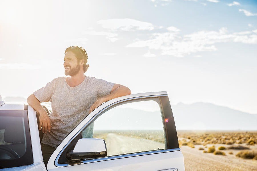Hispanic man standing in car on remote road Photograph by Jacobs Stock Photography Ltd