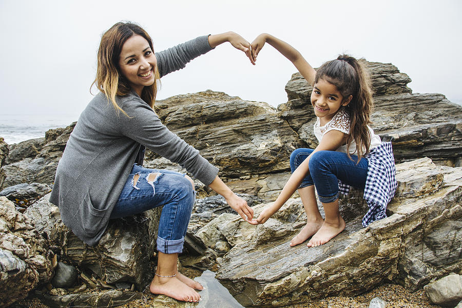Hispanic mother and daughter making heart shape in tide pools Photograph by Shestock