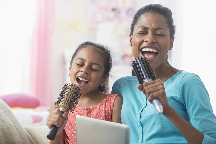 Hispanic mother and daughter singing with hairbrushes and digital tablet Photograph by Jose Luis Pelaez Inc