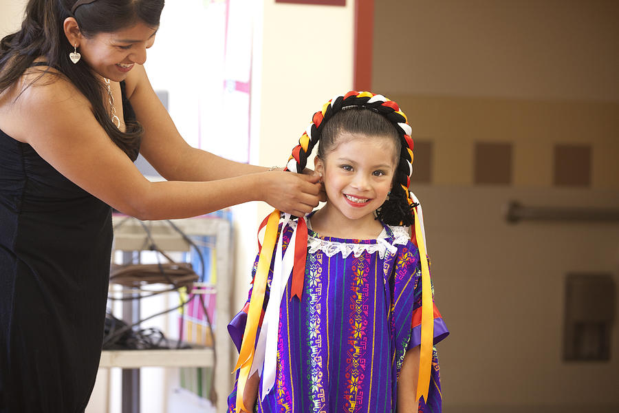 Hispanic mother helping daughter with festive costume Photograph by Sollina Images