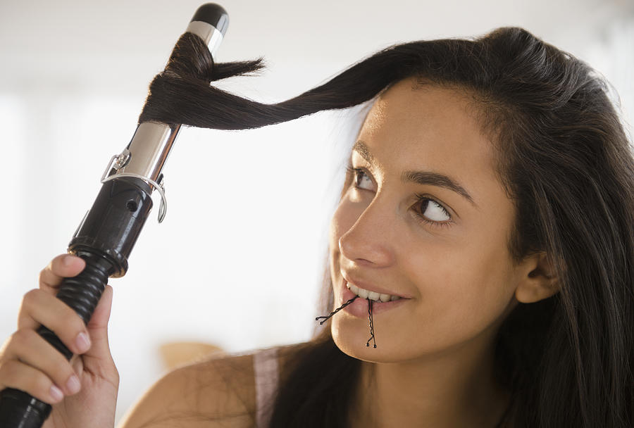 Hispanic teenager curing her hair Photograph by JGI/Jamie Grill