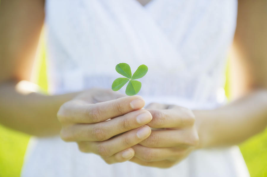 Hispanic woman holding four-leaf clover Photograph by Jacobs Stock Photography Ltd