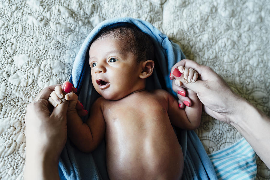 Hispanic woman holding hands of baby boy Photograph by Inti St Clair