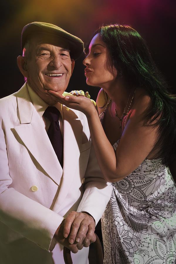 Hispanic woman kissing senior man in nightclub Photograph by Jose Luis Pelaez Inc