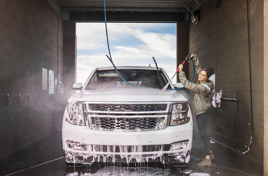 Hispanic woman washing car at self-serve car wash Photograph by Jacobs Stock Photography Ltd