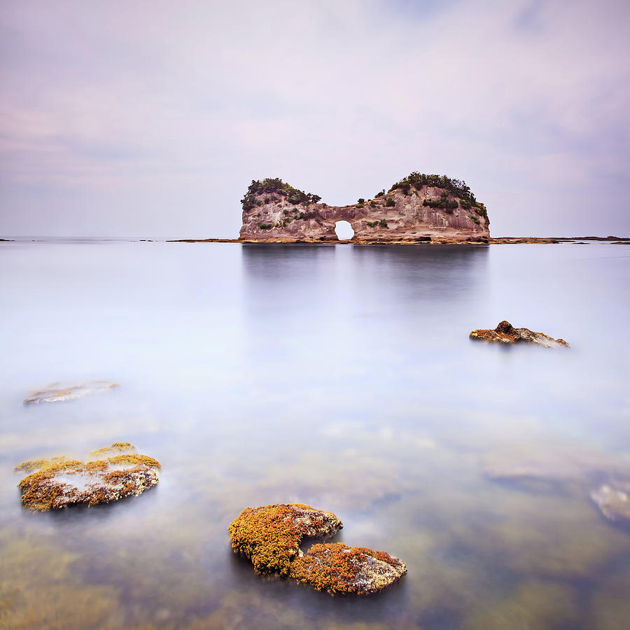Hole island and rocks in a tropical blue ocean. Cloudy sky. Photograph by Stefano Orazzini