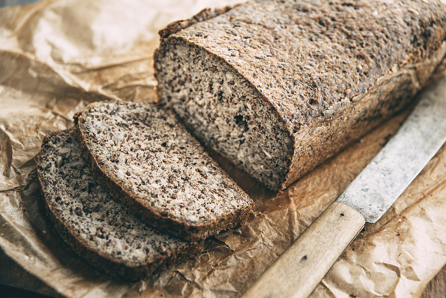 Home-baked wholemeal glutenfree bread and bread knife on brown paper Photograph by Westend61