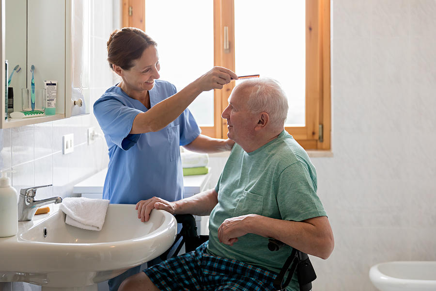 Home Caregiver with senior man in bathroom Photograph by FredFroese