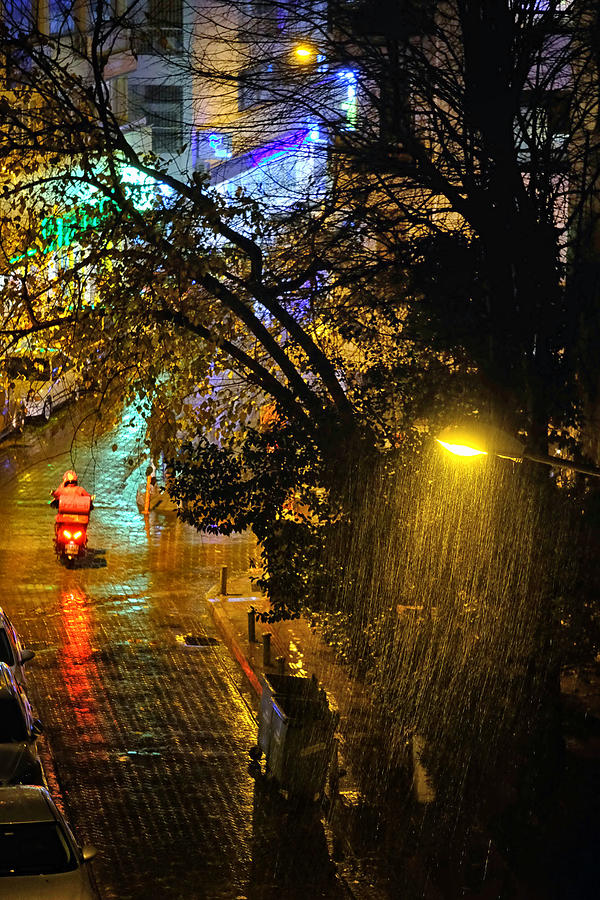 Home delivery bike under rain at night. Photograph by Emreturanphoto