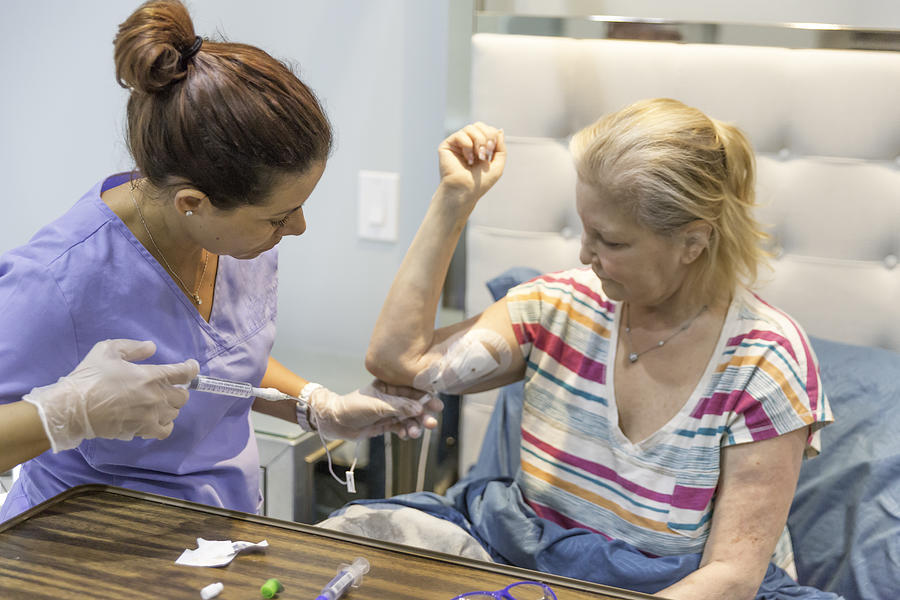 Home healthcare nurse flushing out the picc line of her female patient Photograph by Jodi Jacobson