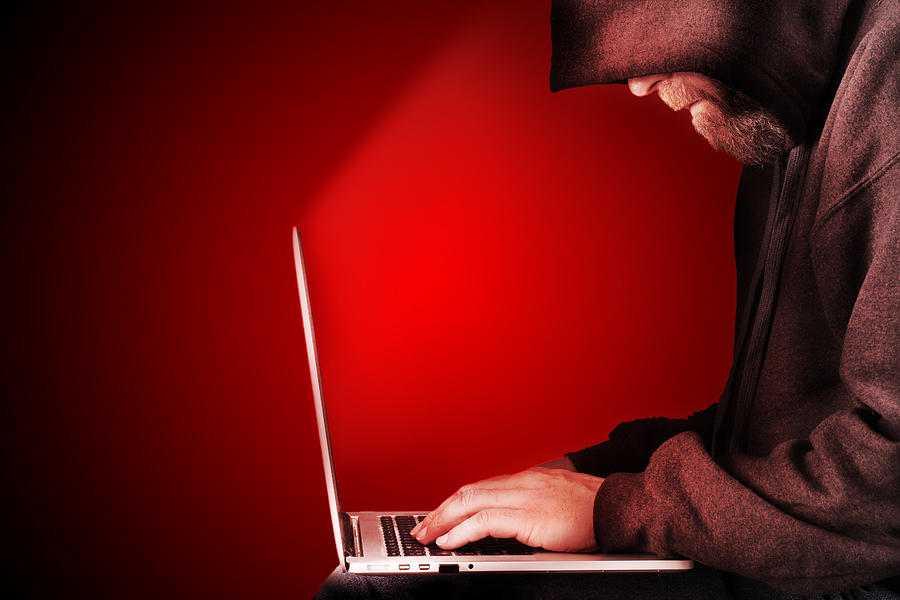 Hooded computer hacker red background Photograph by Simotion