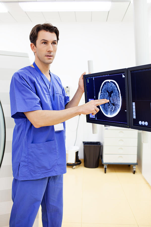 Hospital technician explaining a brain scan Photograph by Alvarez